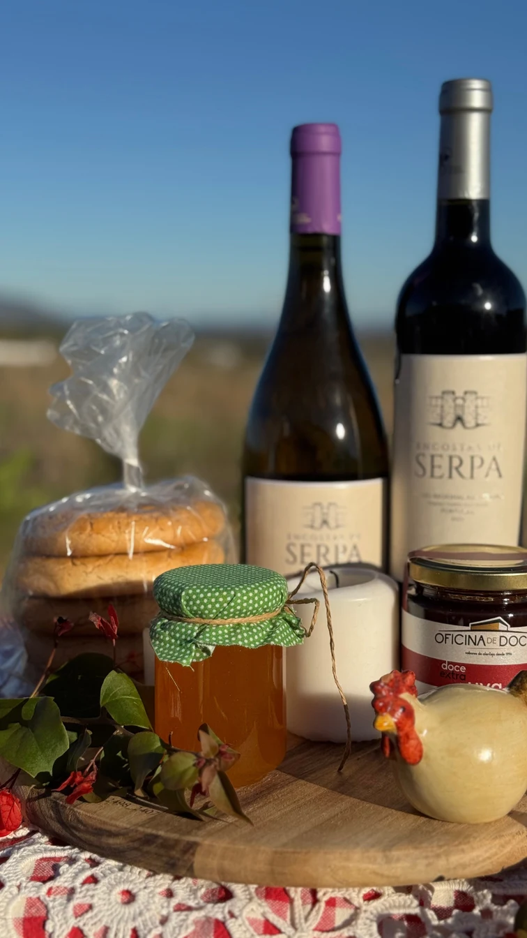 Vinhos, bolos tradicionais, compota e mel numa mesa no campo